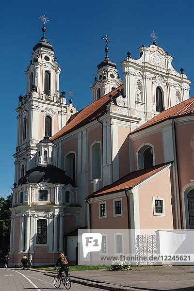 Radfahrer fährt an der erdbeer- und cremefarbenen Barockkirche der Heiligen Katharina vorbei  Altstadt  UNESCO-Welterbe  Vilnius  Litauen  Europa