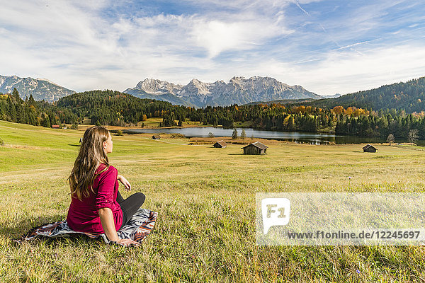 Frau sitzt und starrt auf den Geroldsee und die Karwendelalpen  Krun  Oberbayern  Bayern  Deutschland  Europa