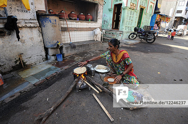 Woman making the day's chapatis on a wood fire in the street outside near the Jama Mosque in old Ahmedabad  Gujarat  India  Asia