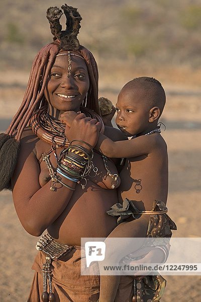 Junge Himbafrau trägt einen Säugling auf ihrem Arm  Kaokoveld  Namibia  Afrika