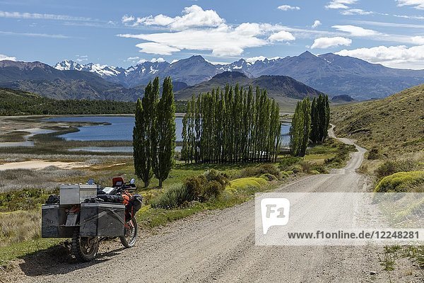 Schwer bepacktes Motorrad auf einer Schotterstraße vor einem See  Valle Chacabuco  Cochrane  Region de Aysen  Chile  Südamerika