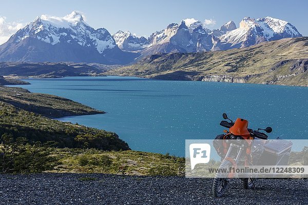 Ein schwer bepacktes Motorrad auf einer Schotterstraße hinter dem Lago del Torro und der Berggruppe Cordillera Paine  Torres de Paine  Region de Magallanes y de la Antartica  Chile.