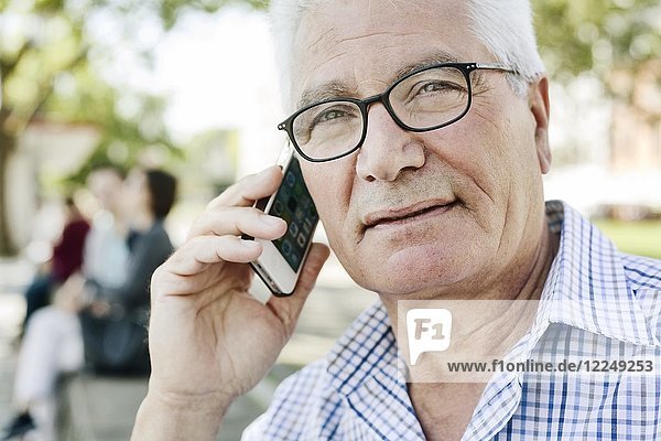 Grauhaariger Senior mit Brille telefoniert mit seinem Smartphone  Deutschland  Europa