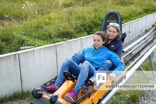 Mutter und Tochter genießen eine Fahrt mit dem Alpine Coaster  Sommerrodelbahn an der Kolbensattelhütte bei Oberammergau  Oberbayern  Bayern  Deutschland  Europa
