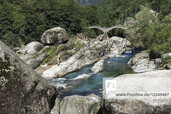 Rock formations  bathing people at Verzasca near Lavertezzo  in the back the Roman bridge Ponte dei Salti  Verzascatal  Valle Verzasca  Canton Ticino  Switzerland  Europe