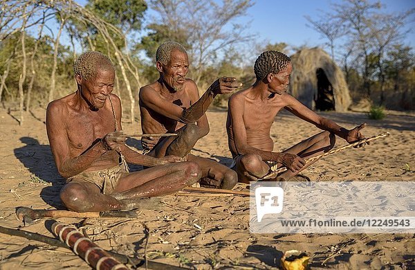 Buschmänner der Ju/' Hoansi-San auf dem Boden sitzend  Dorf //Xa/oba  in der Nähe von Tsumkwe  Otjozondjupa-Region  Namibia  Afrika