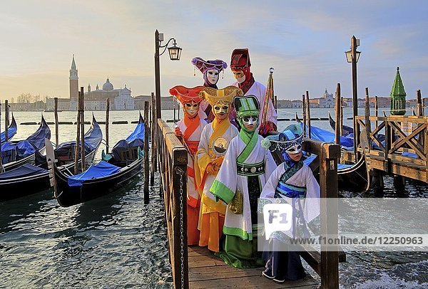 Disguised persons with Venetian masks on walkway at the lagoon  behind island of San Giorgio  carnival in Venice  Italy  Europe
