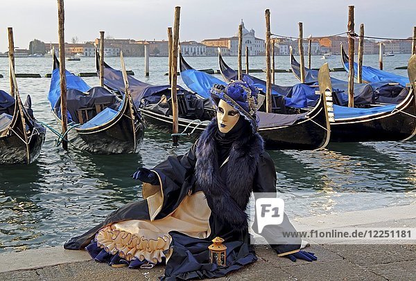 Frau mit venezianischer Maske sitzt an der Lagune hinten San Giorgio Karneval in Venedig Italien Europa