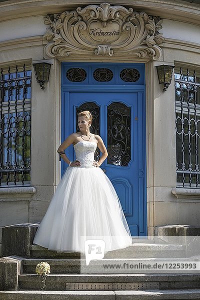 Junge blonde Frau im weißen Hochzeitskleid posiert auf einer Treppe  Schweiz  Europa