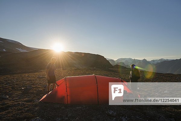 Two persons with red tent  mountain scenery  evening light  Greenland  North America