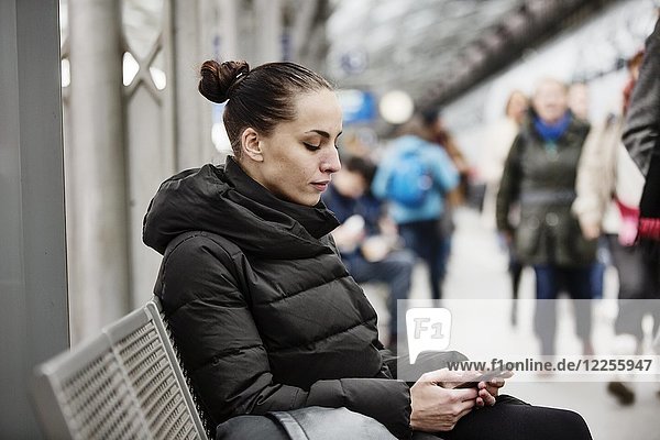 Young woman on a platform in the main station looks at her smartphone  Cologne  North Rhine-Westphalia  Germany  Europe
