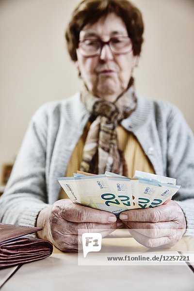 Seniorin sitzt am Tisch und zählt ihr Geld  Deutschland  Europa