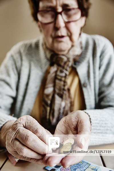 Senior citizen sits at the table and counts her money  Germany  Europe