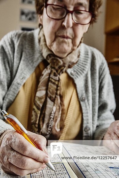 Senior sitzt am Tisch zu Hause und löst Rätsel  Sudoku  Kreuzworträtsel  Köln  Nordrhein-Westfalen  Deutschland  Europa