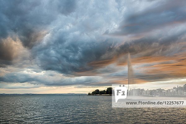 Fontäne und Gewitterwolken bei Sonnenuntergang hinten die Schlosskirche Friedrichshafen Bodensee Baden-Württemberg Deutschland Europa