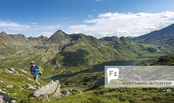 Hiker on a stone  view into the valley on the Giglachsee lakes  Schladminger Höhenweg  Schladminger Tauern  Schladming  Styria  Austria  Europe