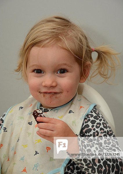 Kleines blondes Mädchen zwei Jahre lächelt isst einen Kuchen Schweden Europa