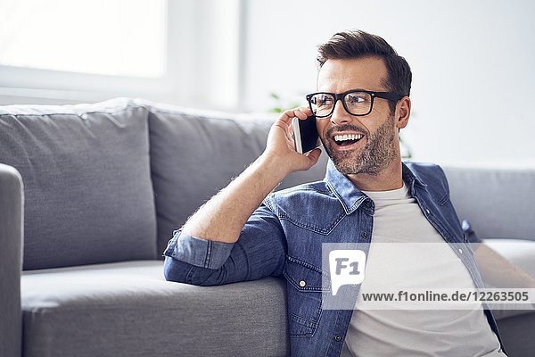 Happy man in living room talking on cell phone