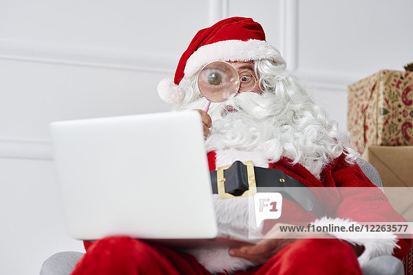 Weihnachtsmann mit Laptop und Lupe