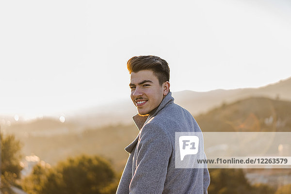 Porträt eines lächelnden jungen Mannes bei Sonnenuntergang