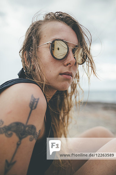 Portrait einer jungen Frau mit Sonnenbrille und Tattoo