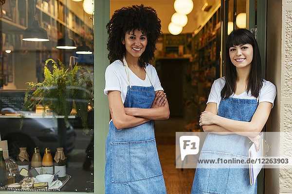 Portrait of two smiling women standing in entrance door of a store