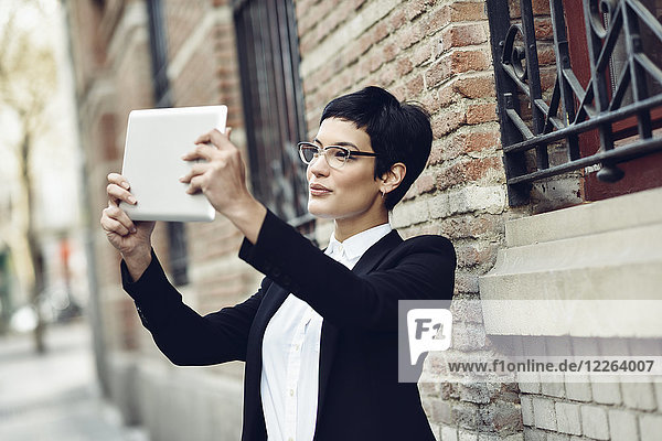 Lächelnde junge Geschäftsfrau nimmt Selfie mit Tablette