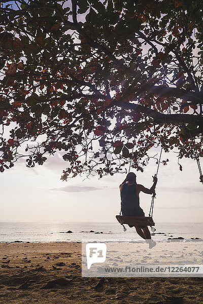 Thailand  Phi Phi Phi Inseln  Ko Phi Phi Phi  Mann auf Baumschaukel am Strand