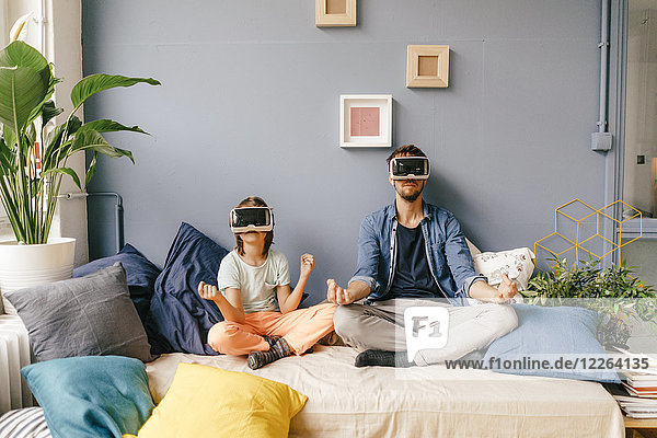 Father and son wearing VR glasses practicing yoga at home