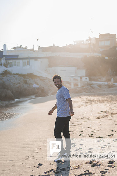 Happy young man strolling on the beach at sunset
