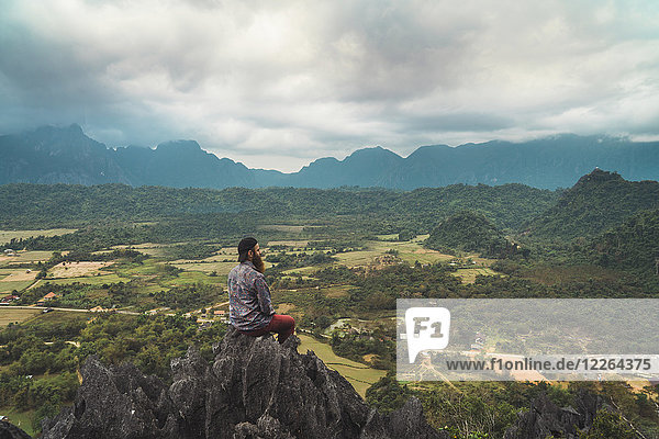 Laos  Vang Vieng  hiker sitting on rock  looking at distance