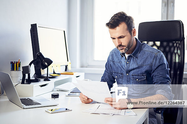 Man reading document at desk in office