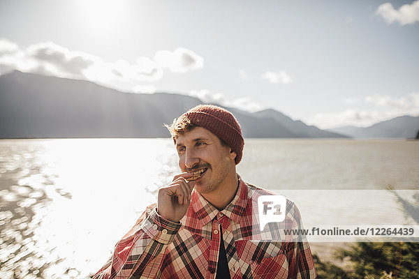 Kanada  British Columbia  Porträt eines lächelnden Mannes beim Essen eines Kekses