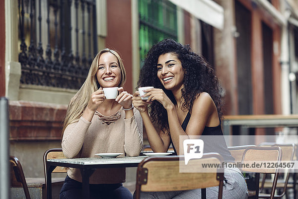 Zwei glückliche Freunde beim Kaffeetrinken im Straßencafé
