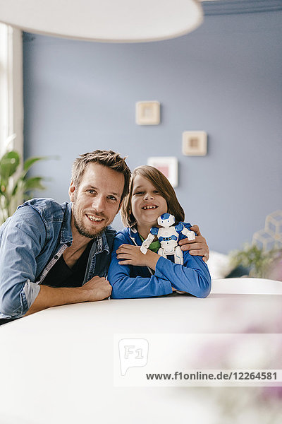 Porträt eines glücklichen Vaters und Sohnes mit Roboter zu Hause
