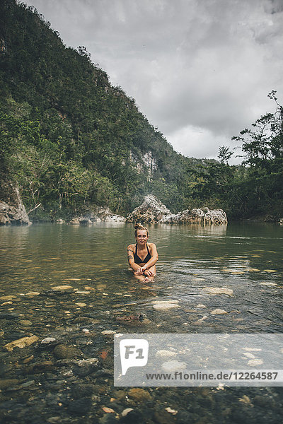 Kuba  Baracoa  Junge Frau sitzend im Yumuri Fluss