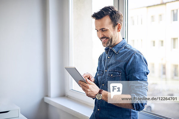 Smiling man using tablet at the window