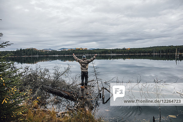 Kanada  British Columbia  Mann steht am Blue Lake und hebt seine Arme.
