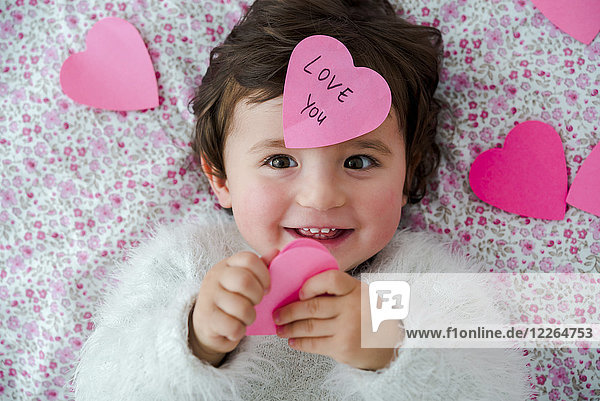 Portrait of baby girl with pink heart-shaped post it stickers