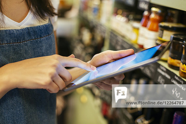 Close-up of woman using tablet at shelf in a store