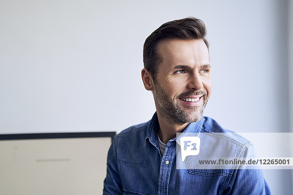 Portrait of smiling man in office looking sideways