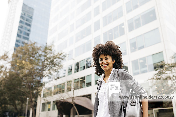 Porträt der lächelnden Frau mit Tasche im Freien