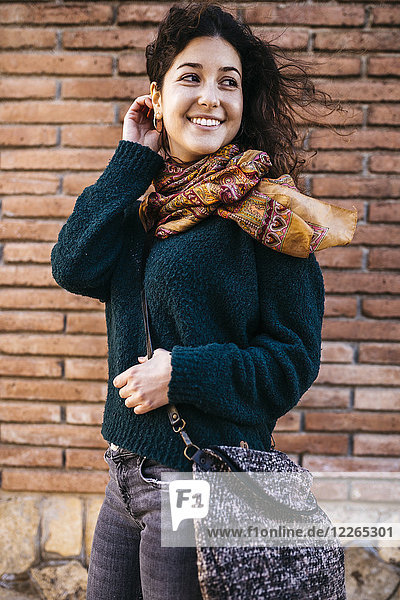 Fashionable woman with bag at brick wall