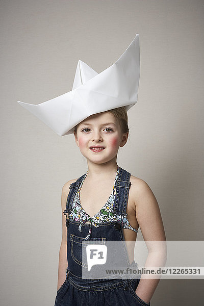 Portrait of little girl with big paper boat on her head