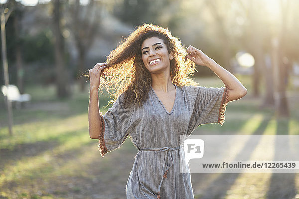 Portrait of happy young woman in a park at backlight
