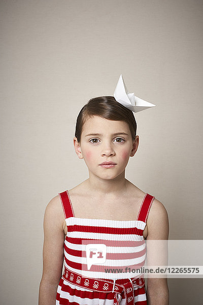 Porträt des kleinen Mädchens mit Papierboot auf dem Kopf