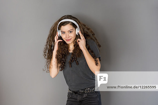 Porträt eines Mädchens mit lockigem Haar  das Musik mit Kopfhörern hört.