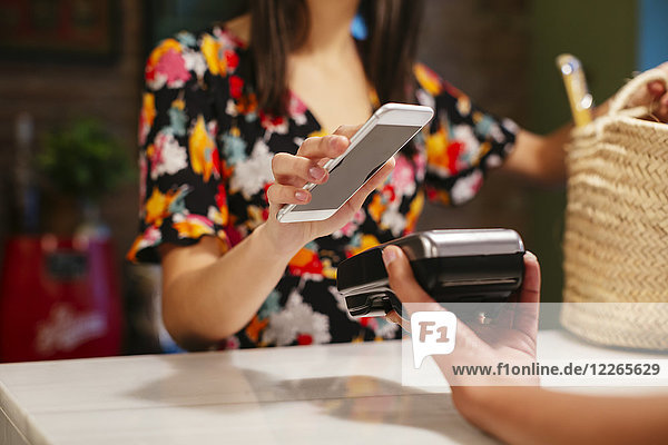 Nahaufnahme des bargeldlosen Bezahlens mit dem Smartphone am Schalter eines Ladens
