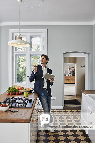 Mann mit Tablette in der Küche mit Blick auf die Deckenlampe
