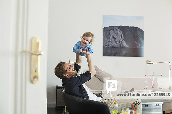 Father lifting up his daugther in living room